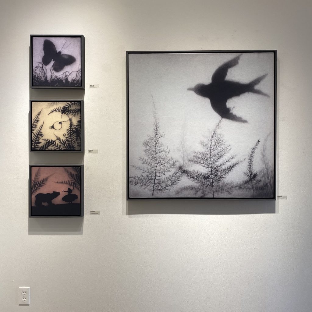 Installation view of 'swan, swan, spiderweb' at Cole Pratt Gallery, New Orleans. Three small stacked images on right (butterfly, ring, bear) aligned with one large canvas on left, featuring a bird in flight on a pale blue background.