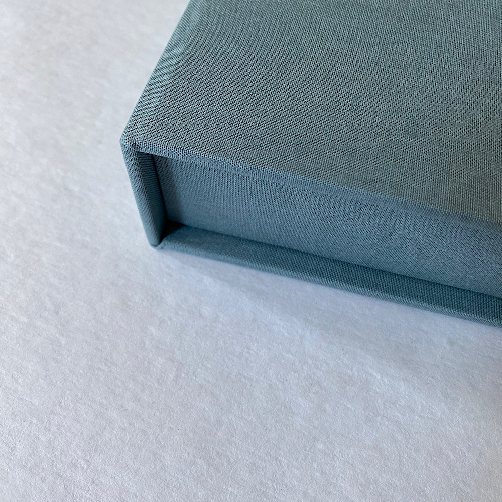 Corner detail of blue cloth-covered portfolio box.